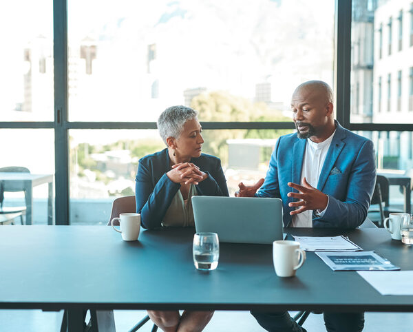 Business, presentation and man on a laptop in a corporate conference or office collaboration with a woman at work. Businessman, manager or coach for marketing, strategy and sales working with CEO.